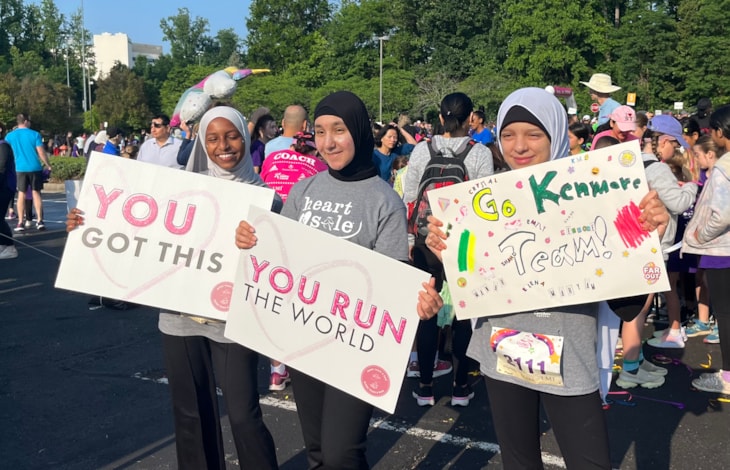 Three Girls on the Run participants holding cheer signs at the 5K.